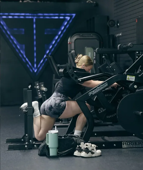 Member using a seated strength machine beneath blue lighting