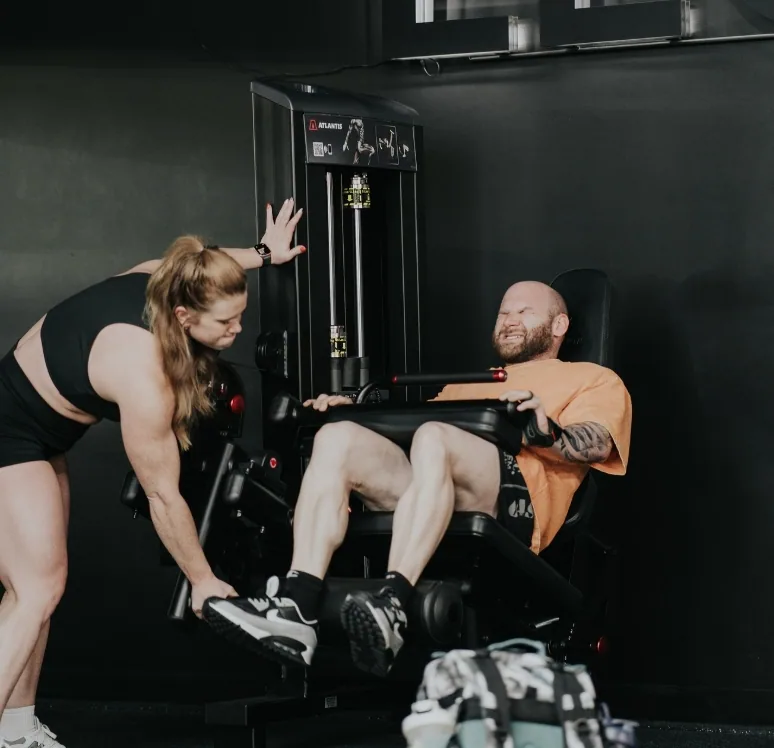 Trainer assisting a member on a strength machine