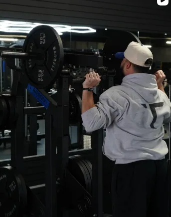 Member lifting a barbell on the training floor